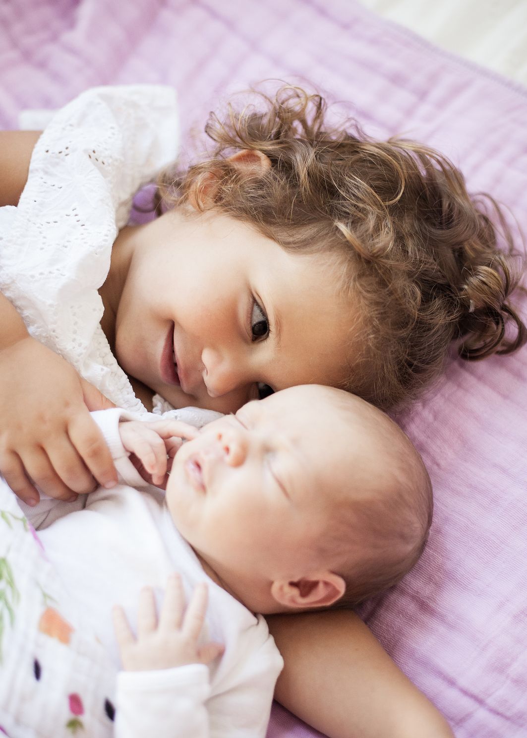 Toddler and newborn girls snuggling together