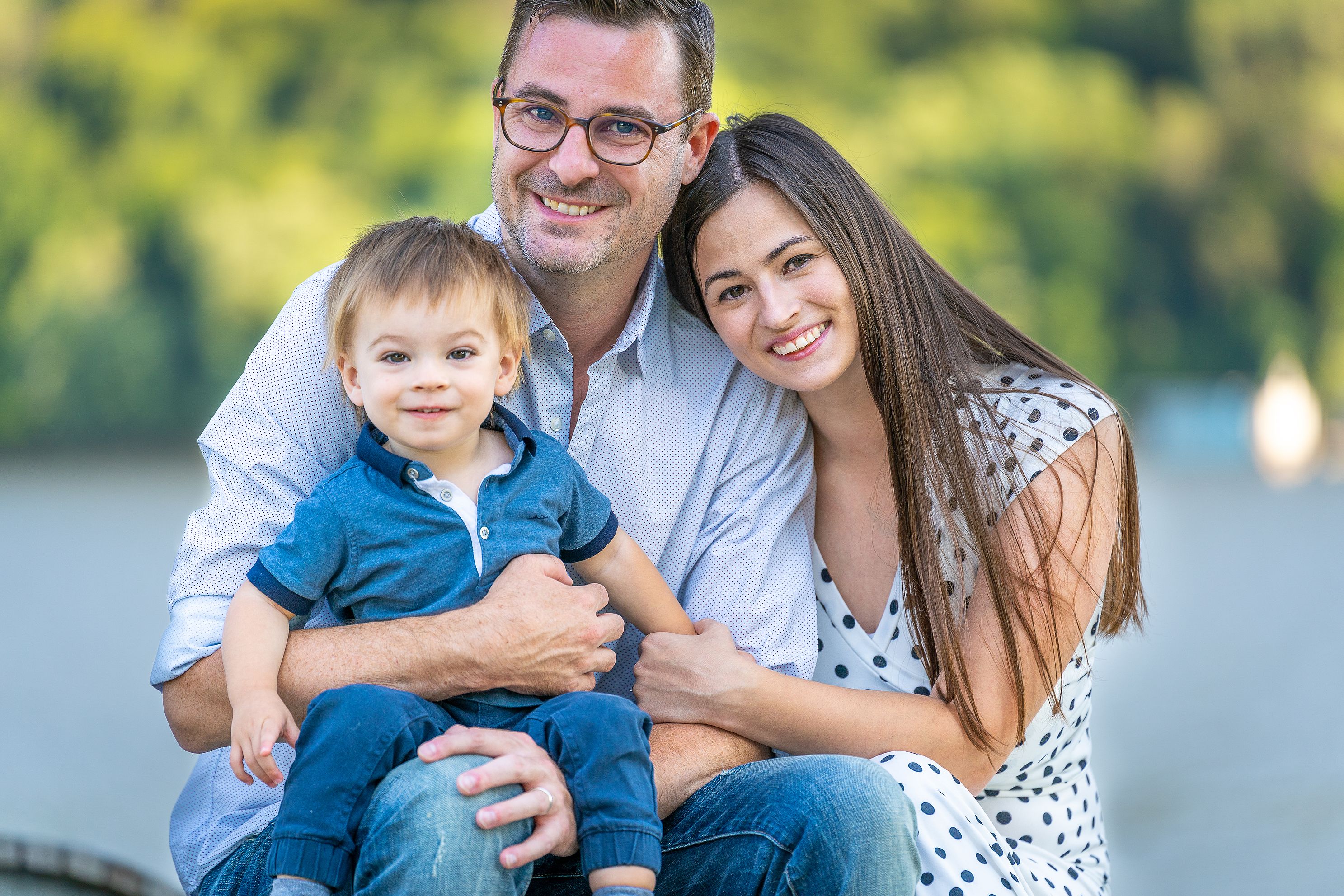 A young family of three poses for a photo.