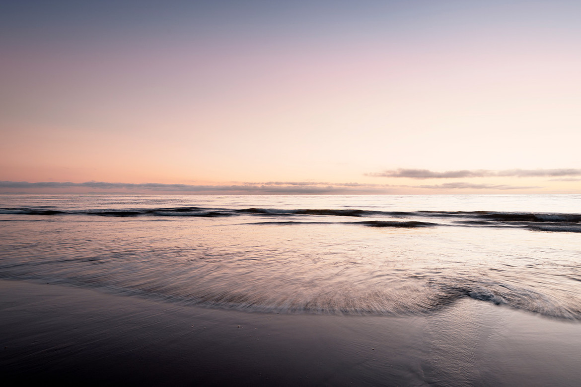 Wispy Ocean Waves break along a stretch of California beach.