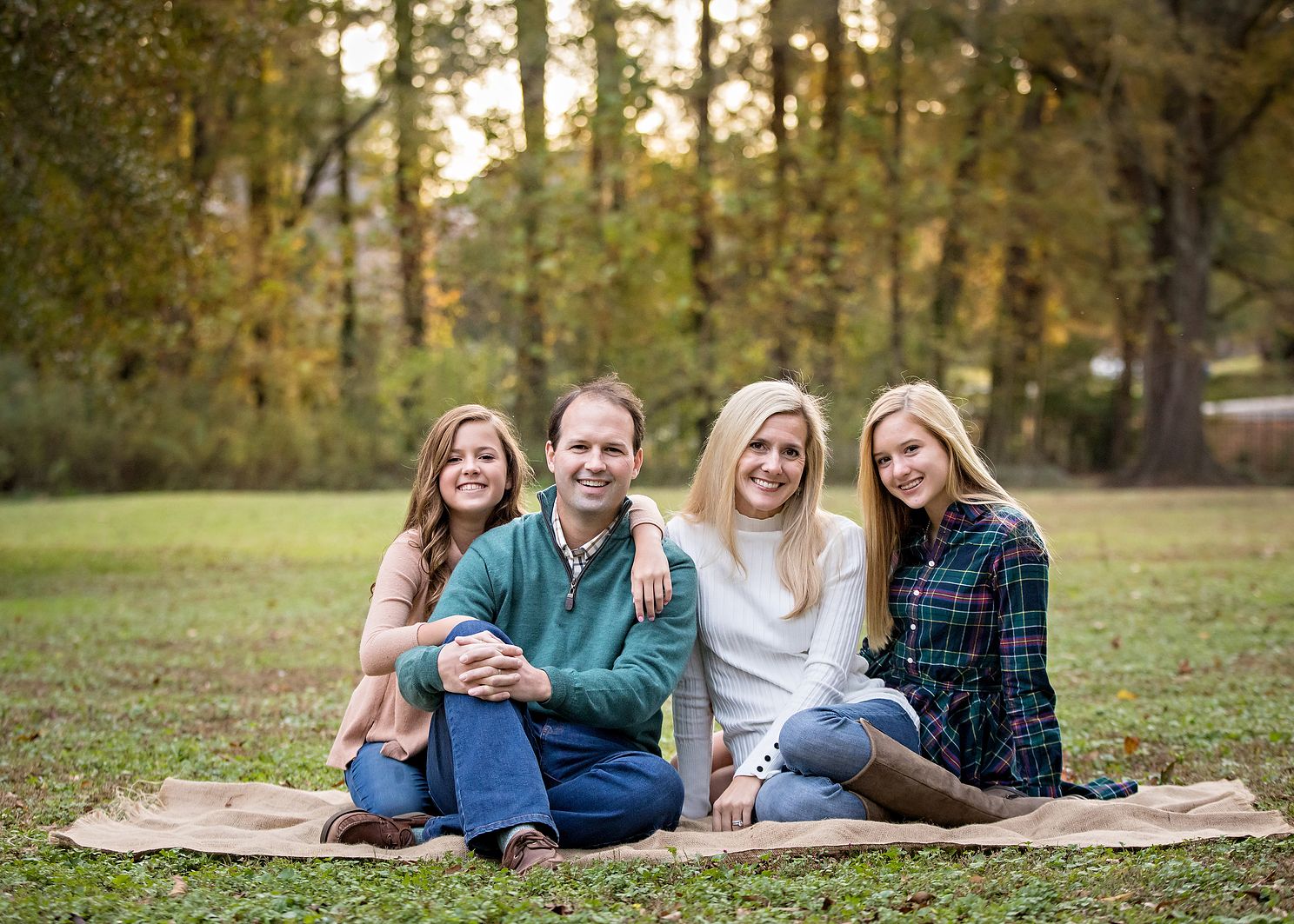 family sitting at sunset embracing each other