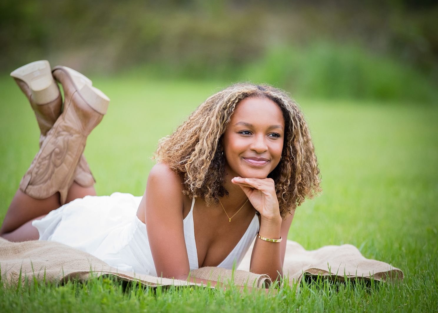 Female laying on stomach with head propped on hand smiling