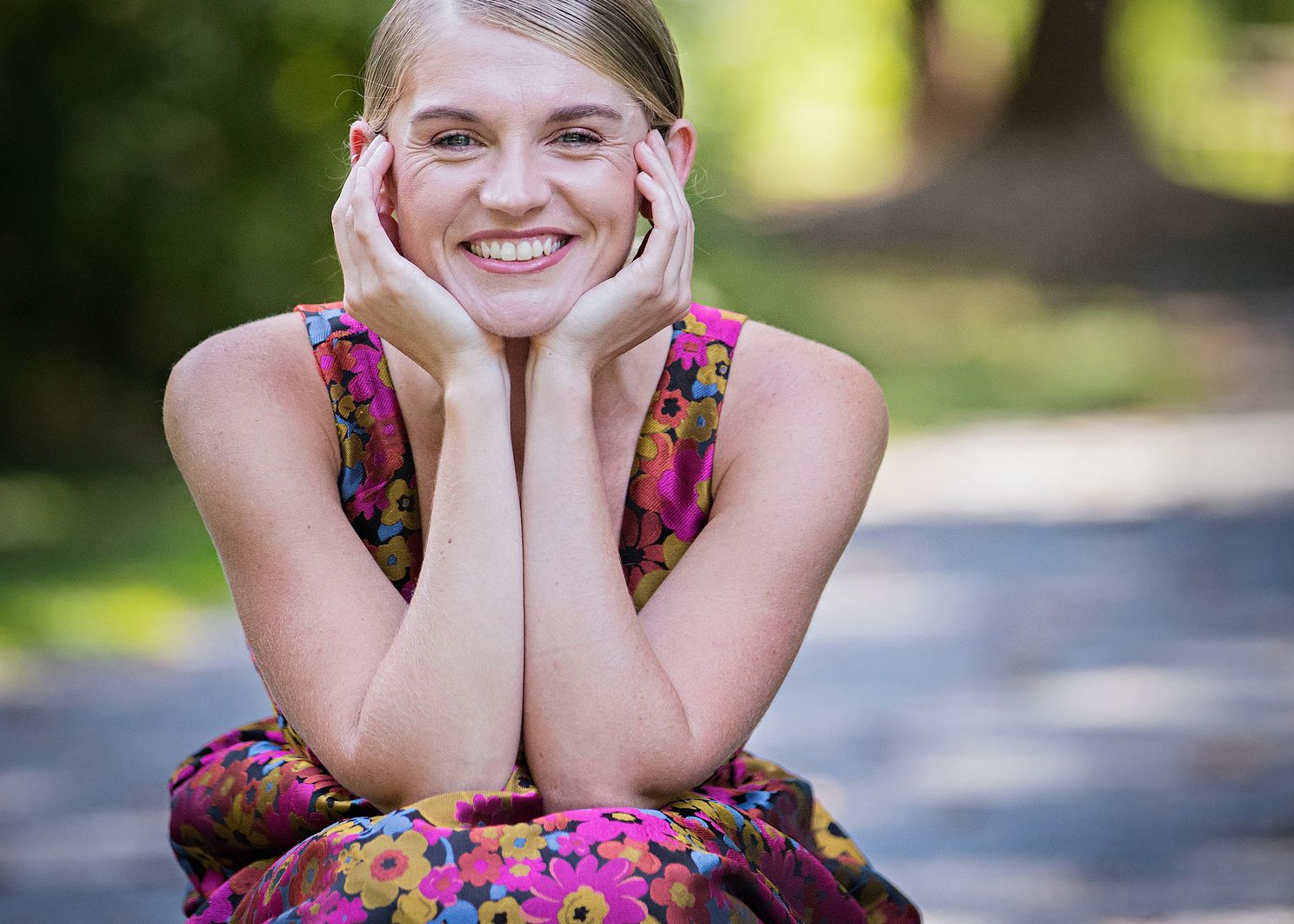 Closeup of woman sitting with hands supporting head smiling at camera