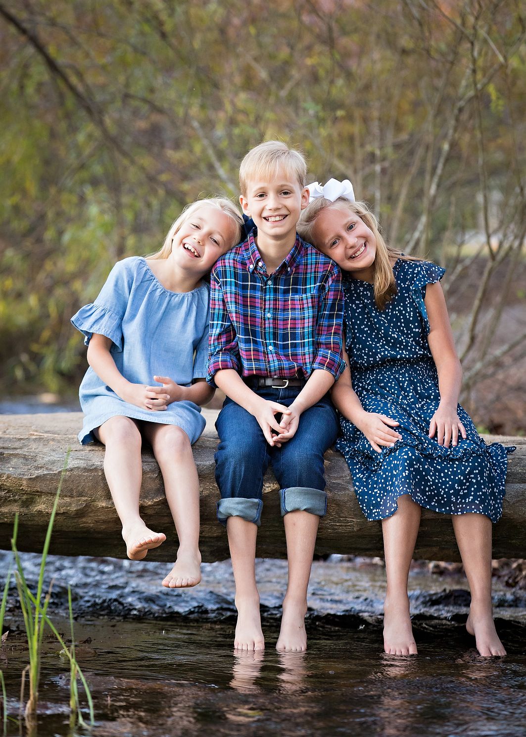 Siblings sitting on a rock with feet in the water