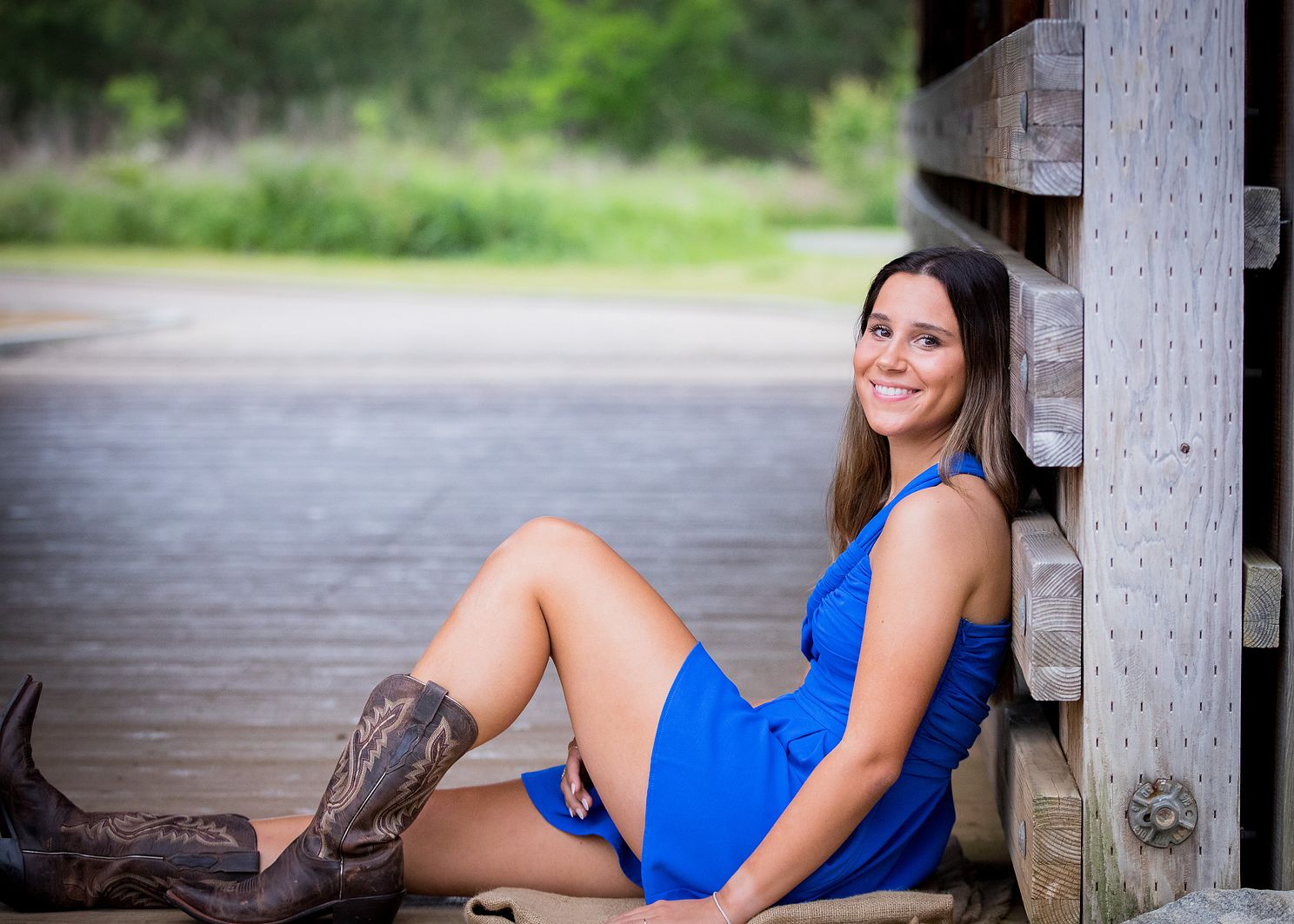 Female senior sitting with knee bent, leaning up against rustic wooden railing