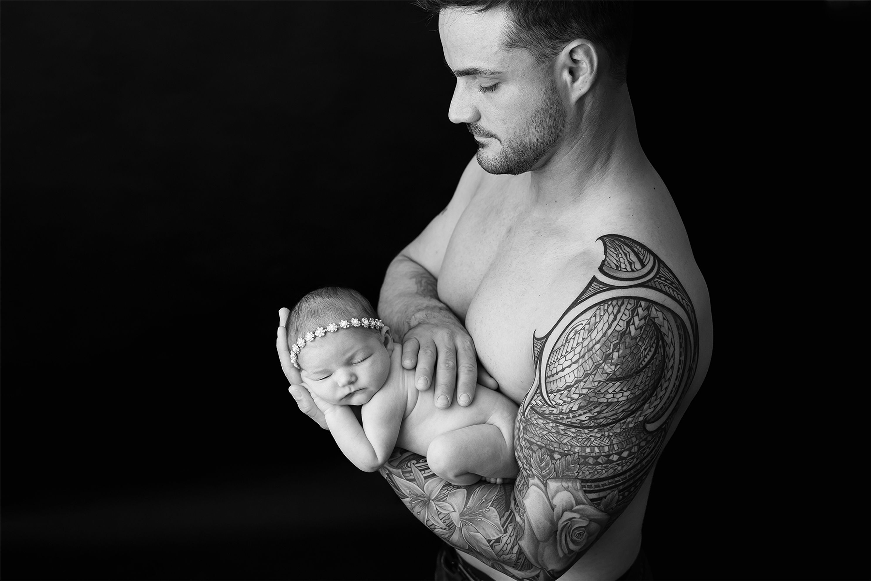 Black and White image in studio, Dad holding naked baby with diamond headband Accredited Photography