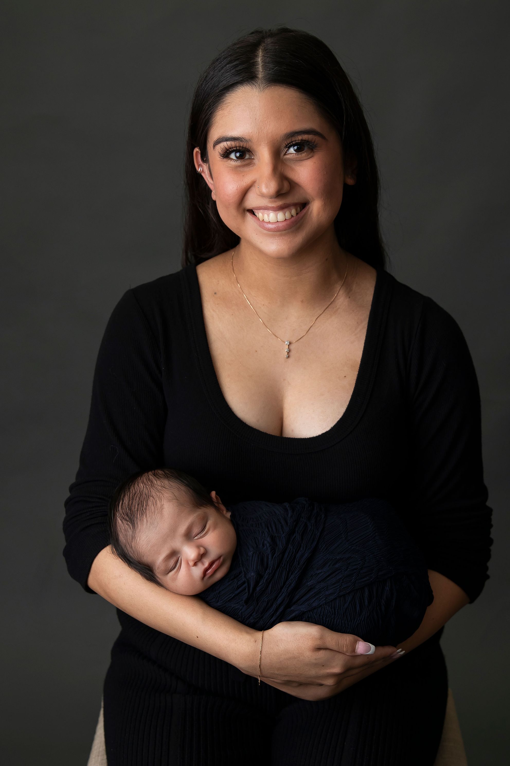 In studio mother and son image, newborn baby 14 days old, wrapped in navy, Mum wearing Black blouse