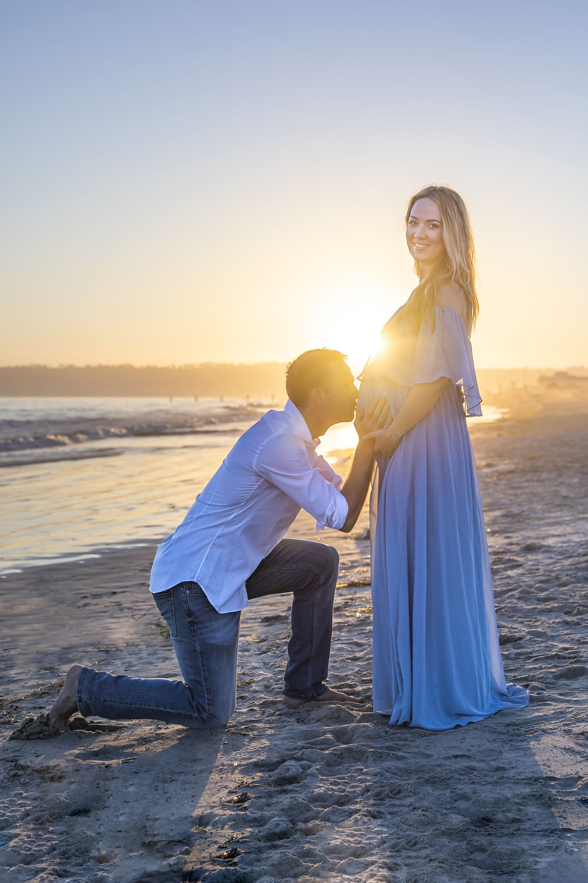 Sunset beach image at maternity shoot, kiss on the bump at sunset. Accredited Photographer