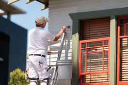 A painter meticulouly paints the trim on a home in San Diego