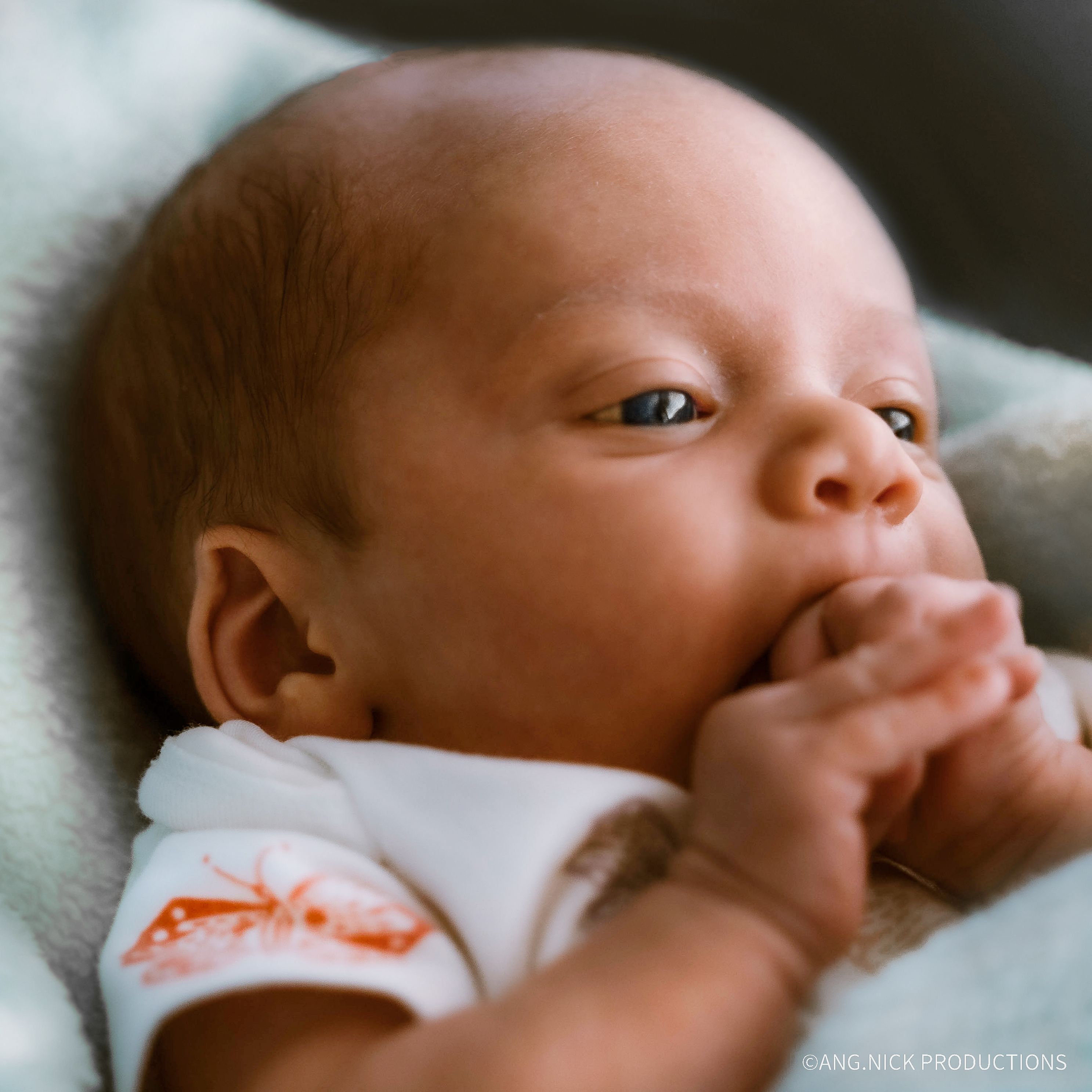 newborn baby girl chewing on her hand
