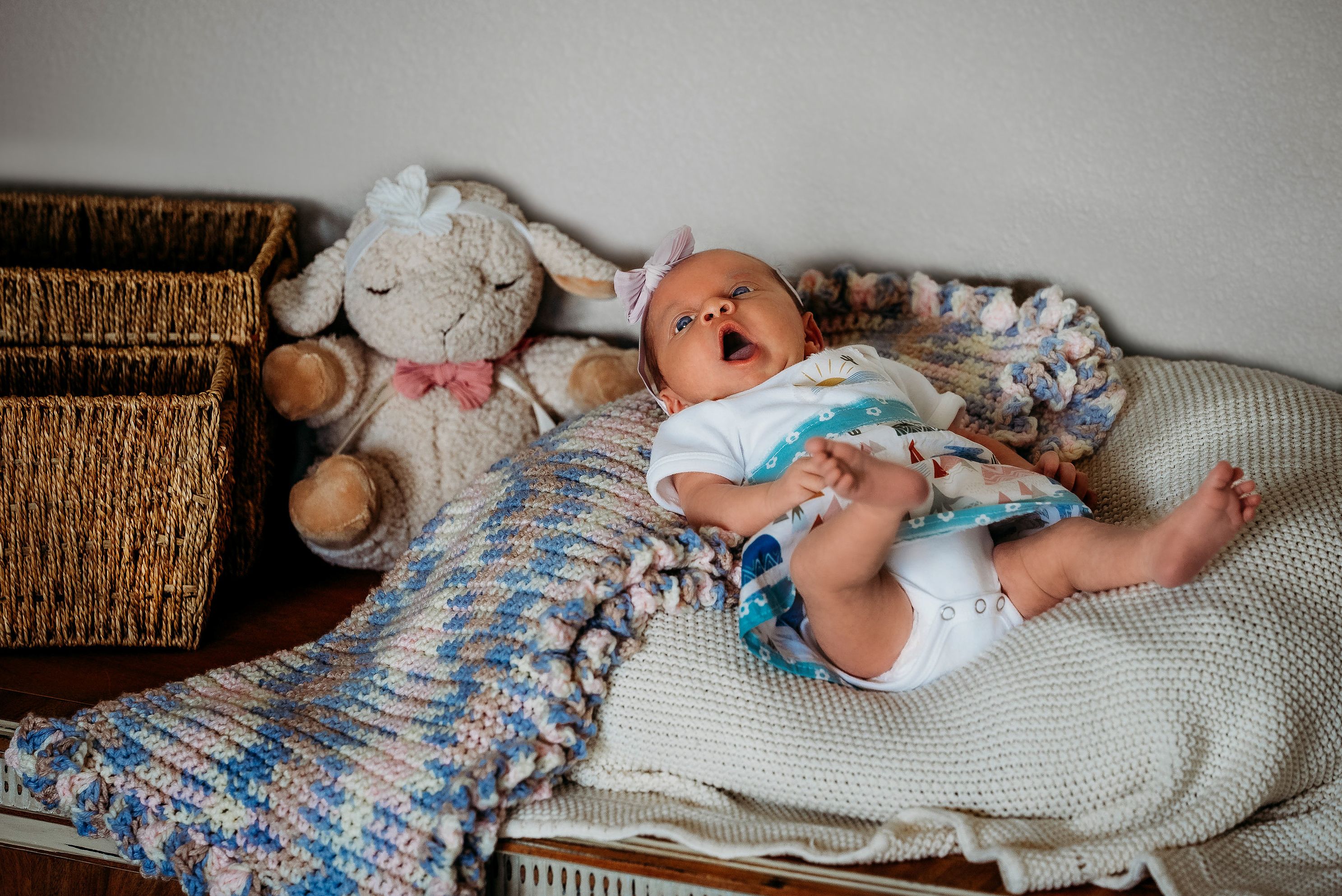 baby laying on soft blankets near her stuffed lamb