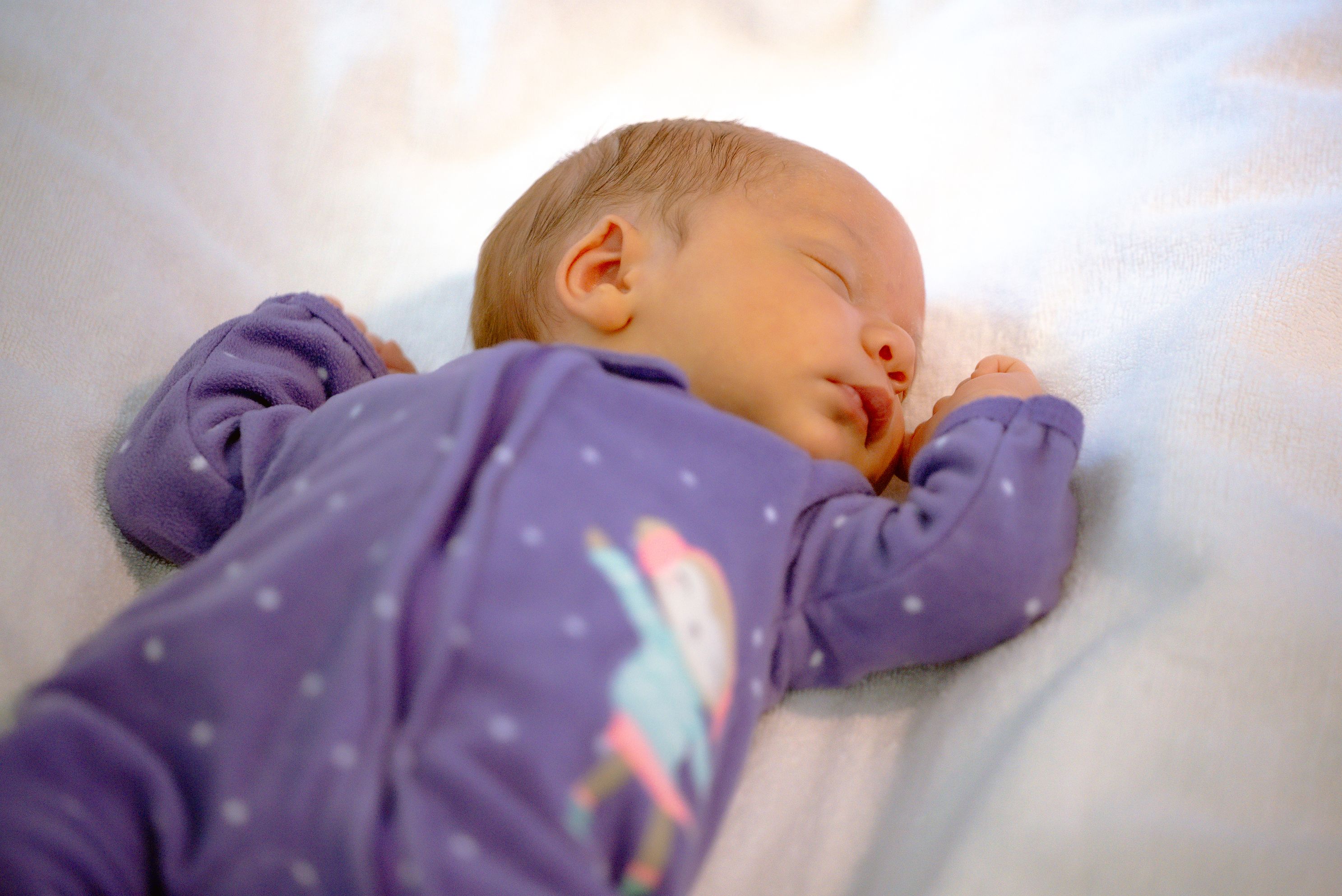 Sleeping infant in purple onesie.