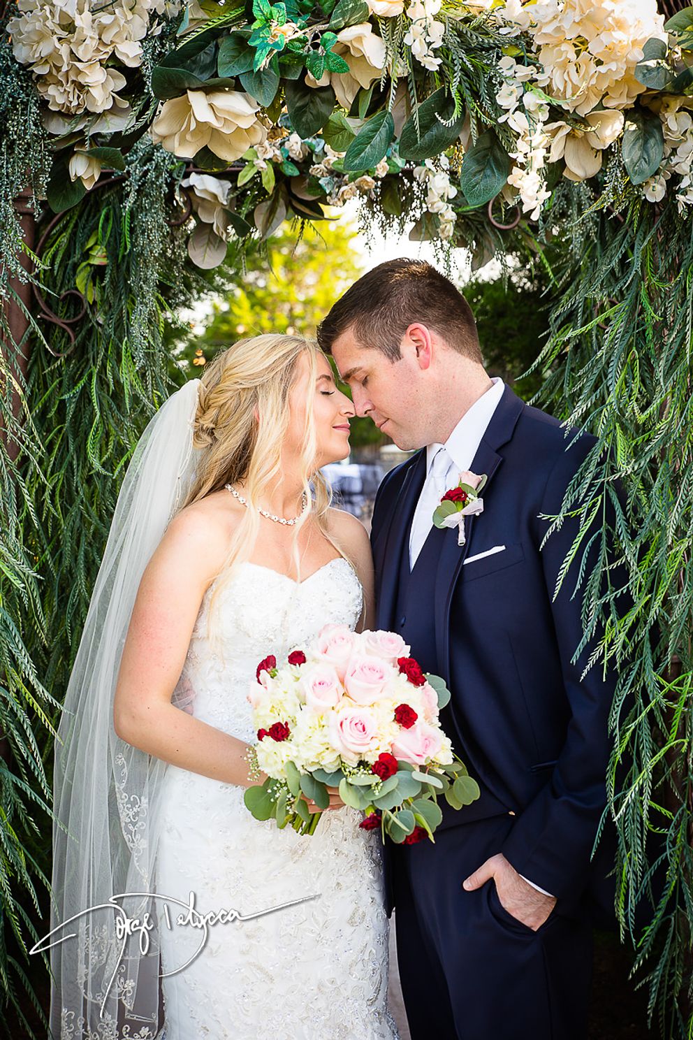 Oklahoma Bride and groom standing under a floral archway, sharing a romantic moment