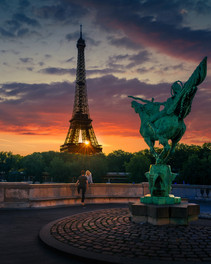 Sunrise over the Eiffel Tower viewed from Pont dIna in Paris with dramatic orange clouds and an eque