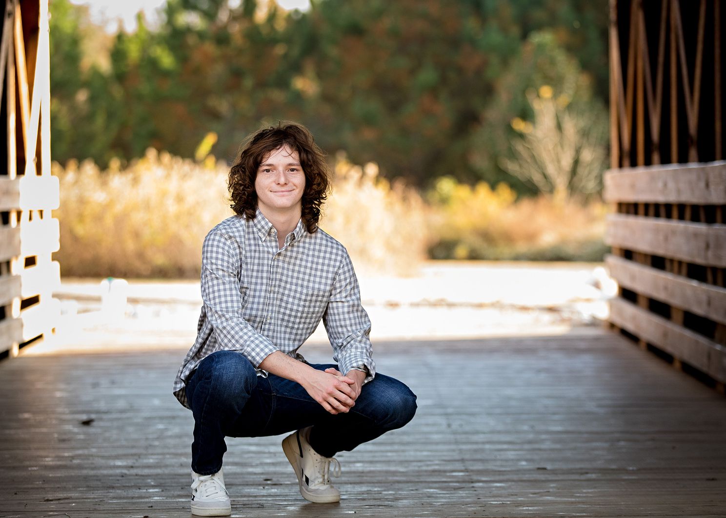 Senior kneeling and smiling under covered bridge