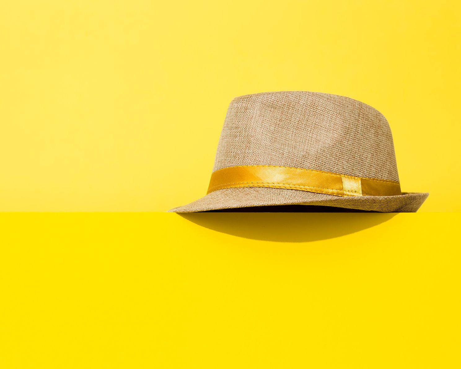 Ladies hat with yellow ribbon accent on yellow background