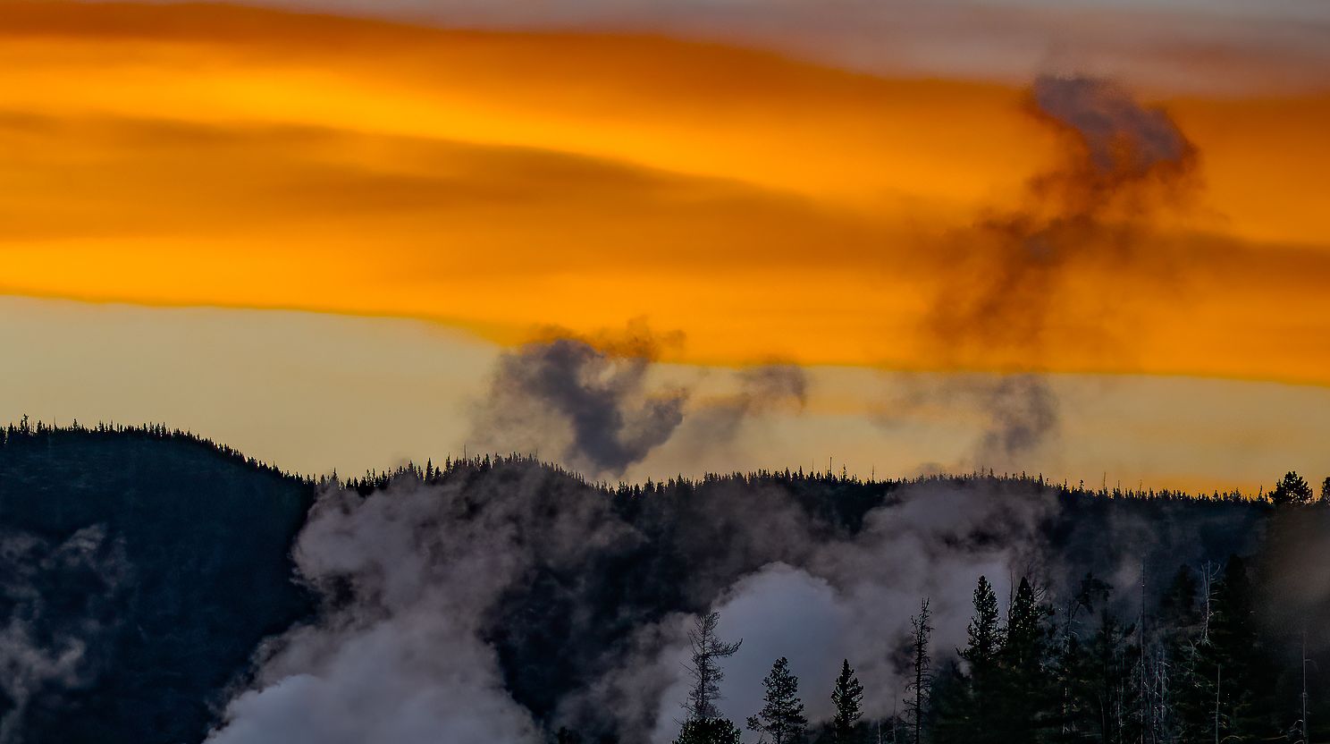 Yellowston geysers near Old Faithful spouting at sunset