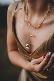 Gold necklace on bare chest in warm light