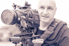Sepia-toned photo of Emmanuel Avargués shooting with a professional video camera on a shoulder rig