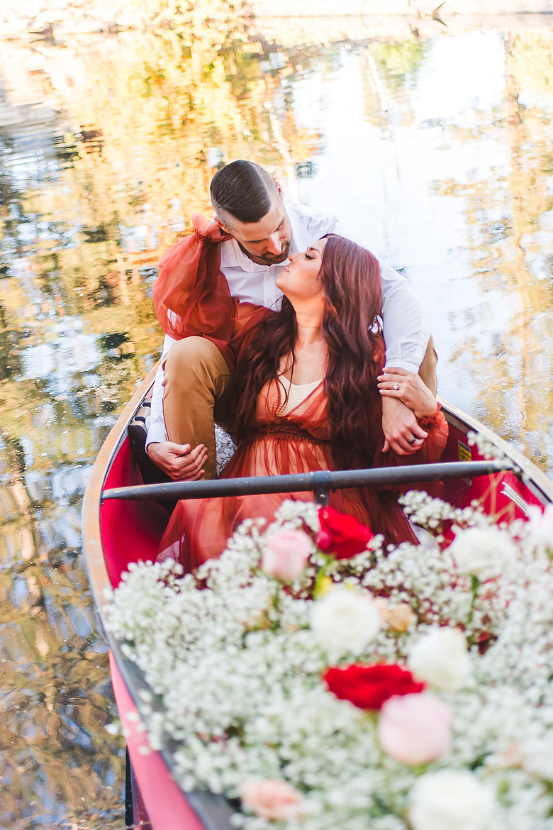 Couple on a boat surrounded by florals on a lake.  Shot by ShootAnyAngle.com