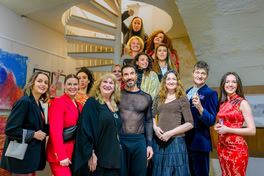 Artists pose confidently on steps, showcasing style, unity, and creativity in a striking portrait