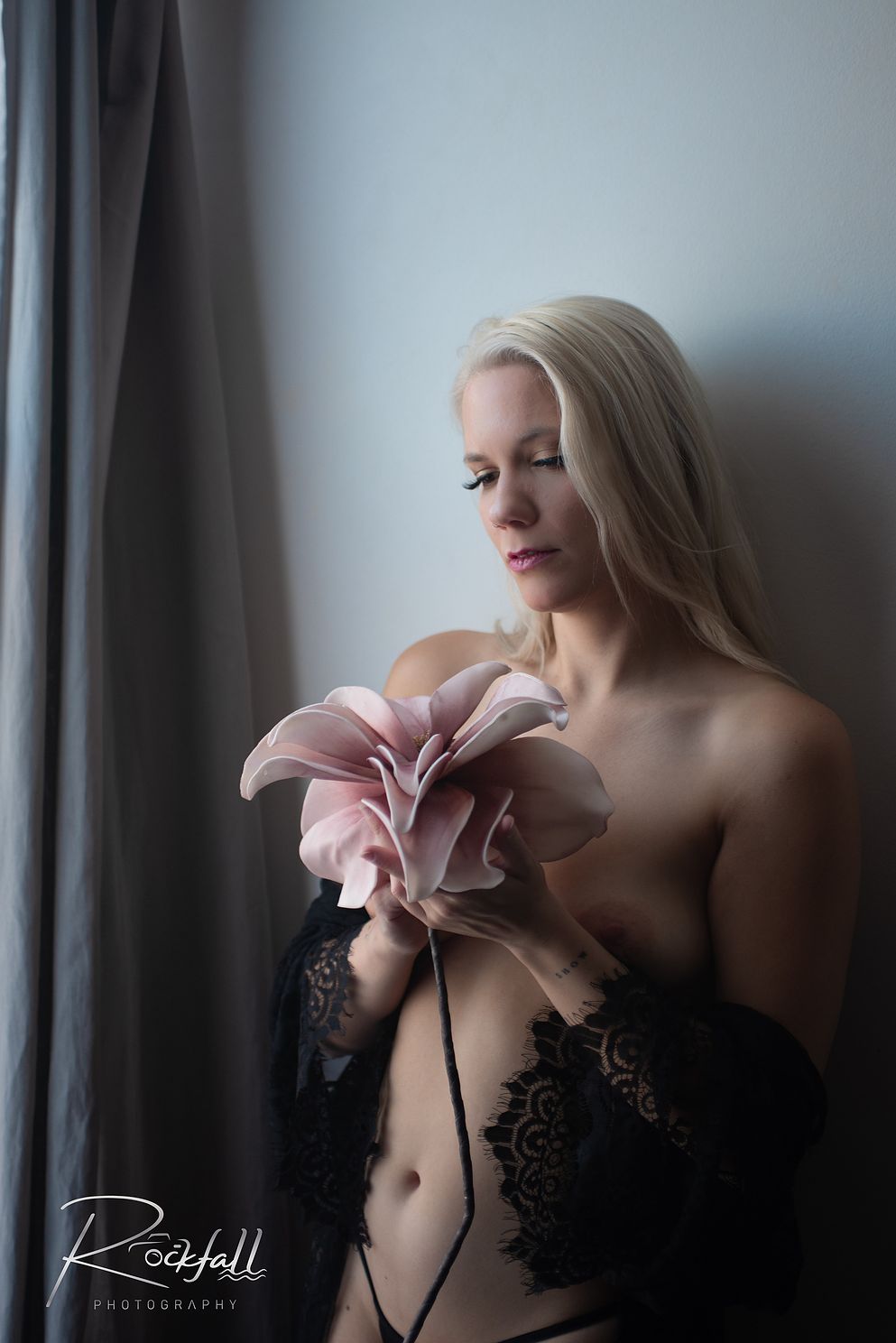 Woman  admiring flower at window boudoir