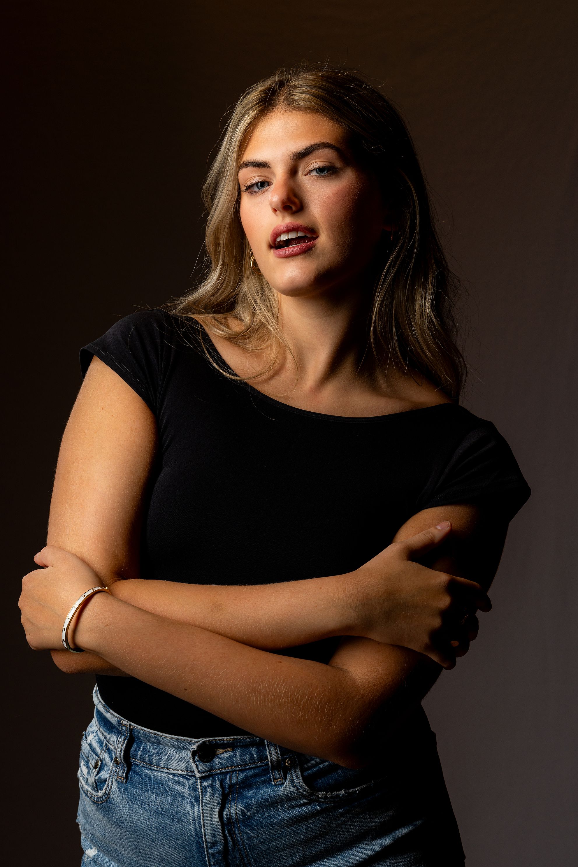 A person wearing a black top poses with crossed arms.
