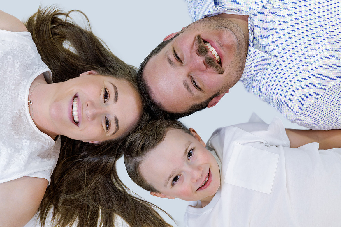 Happy family lying on the ground with their heads together, smiling and sharing a joyful moment.