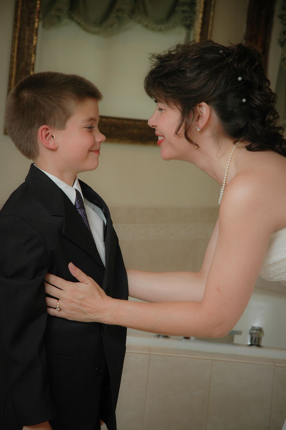 DSCjpg  Smiling bride sharing special moment with her son in hotel room before the wedding ceremony