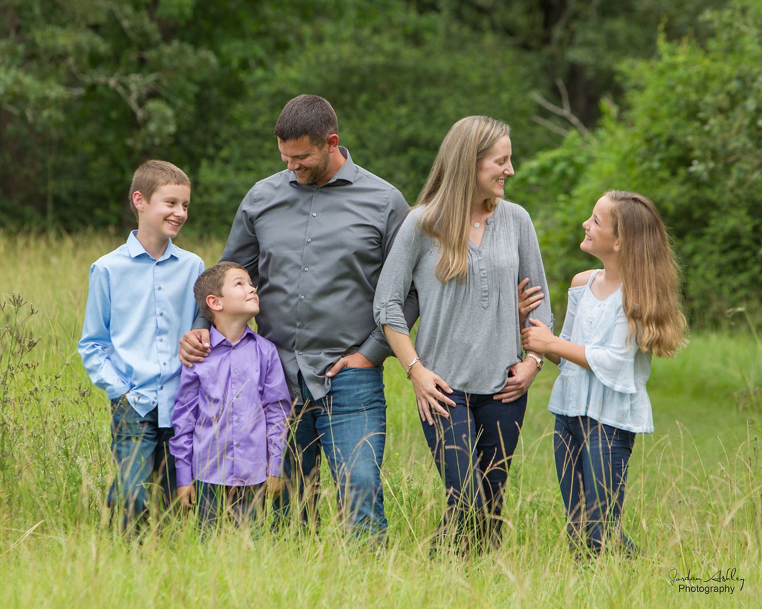 Family portrait of three kids and parents standing in the grass
