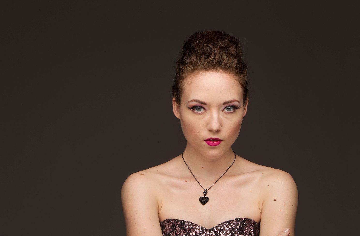 senior photography portrait of high school student in black sweetheart top with a top bun.