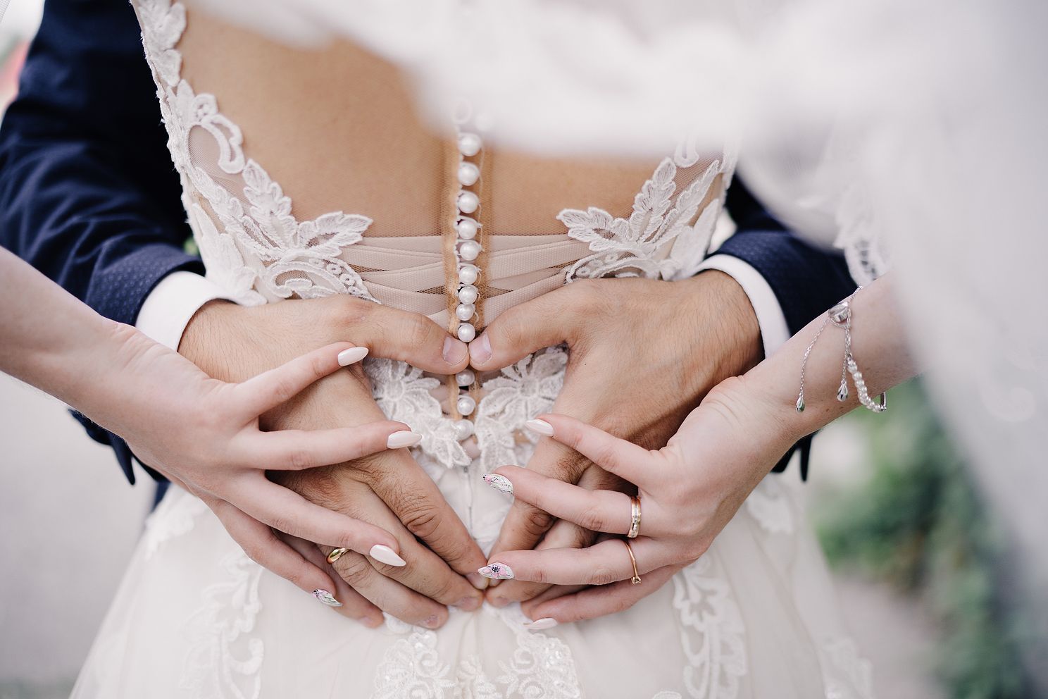 wedding photo of wedding rings on the hands of a couple heart