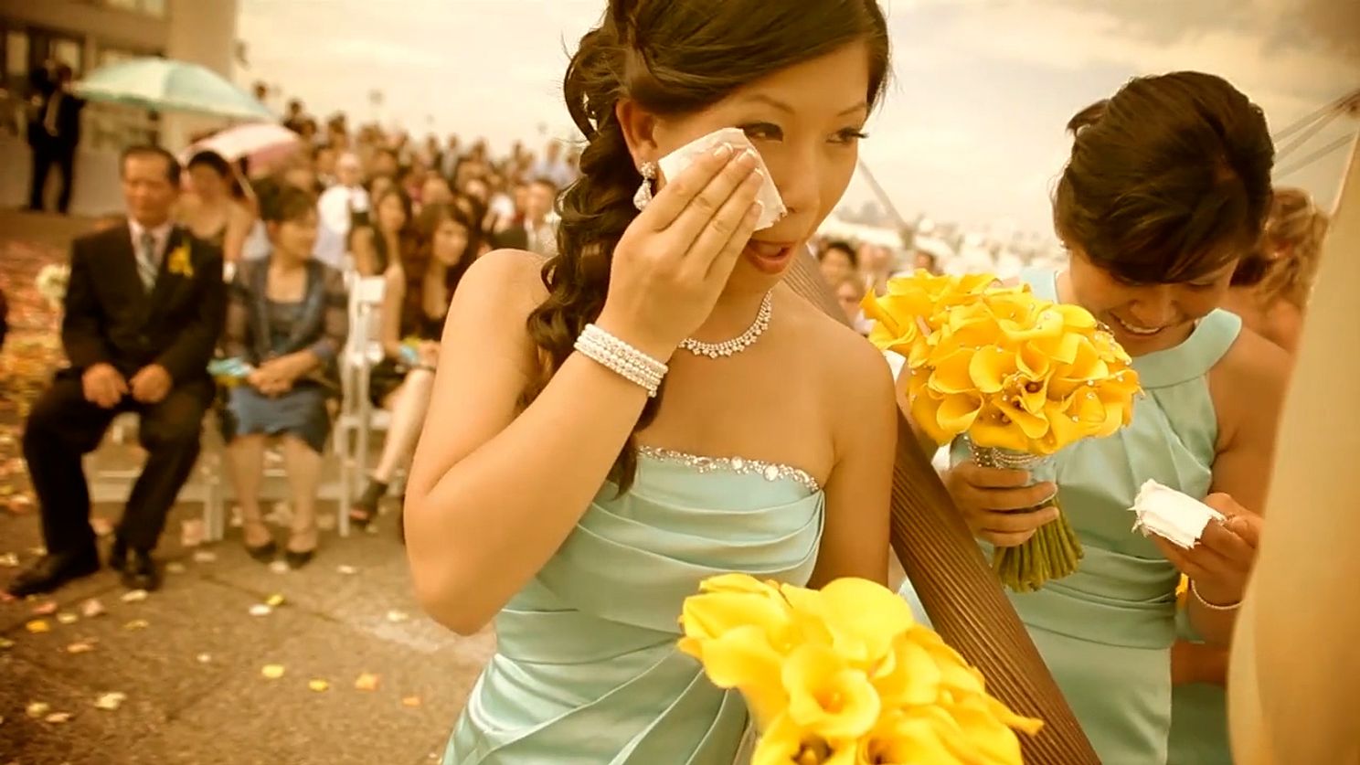 Asian wedding guest dabbing her face