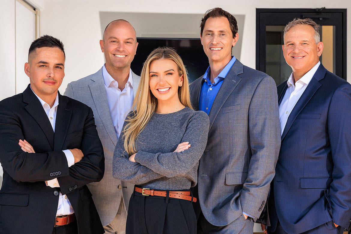 Team photo five professionally dressed people smiling standing indoors