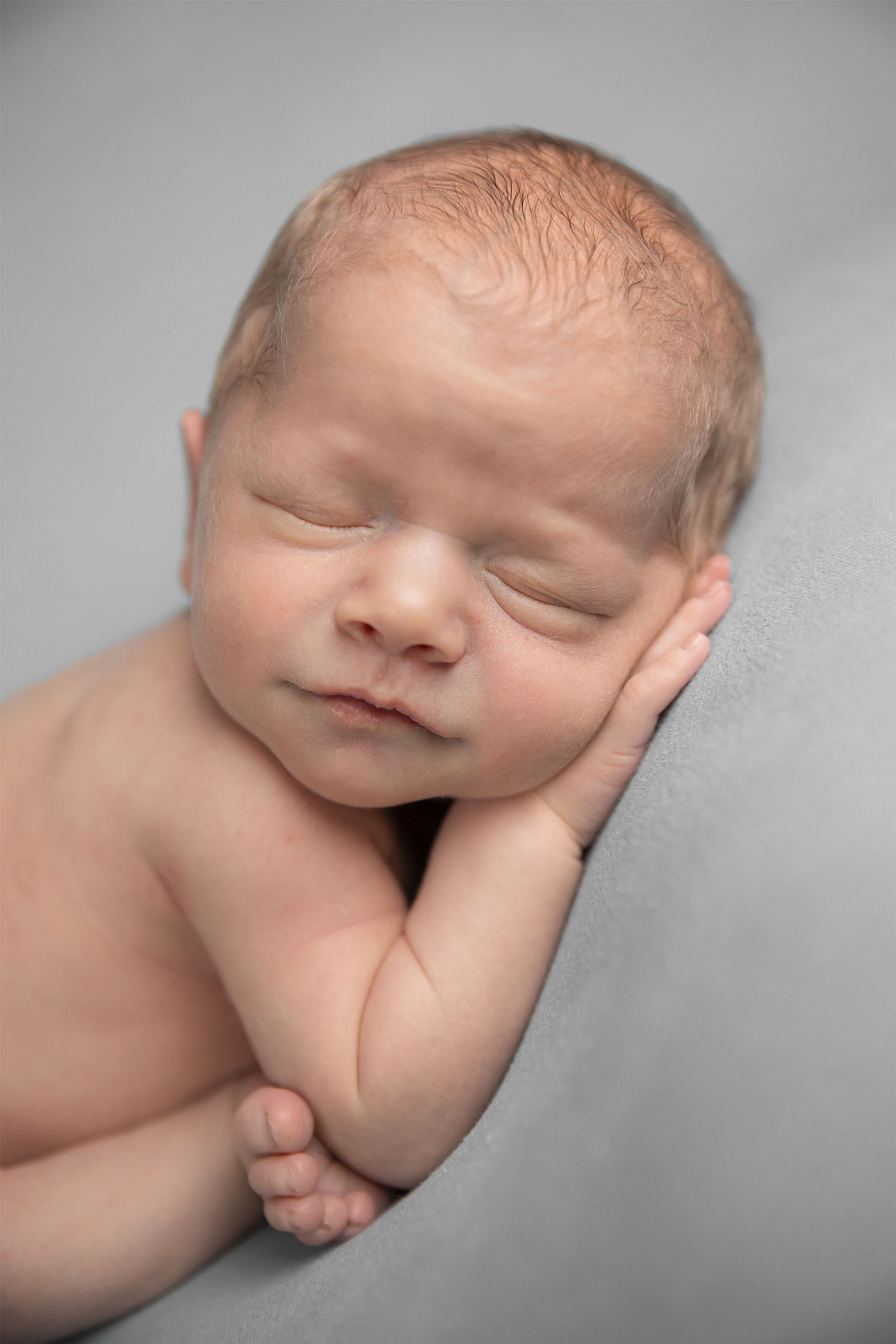 newborn 7 days new, womb position, portrait, Grey background, in home studio. Accredited Photography