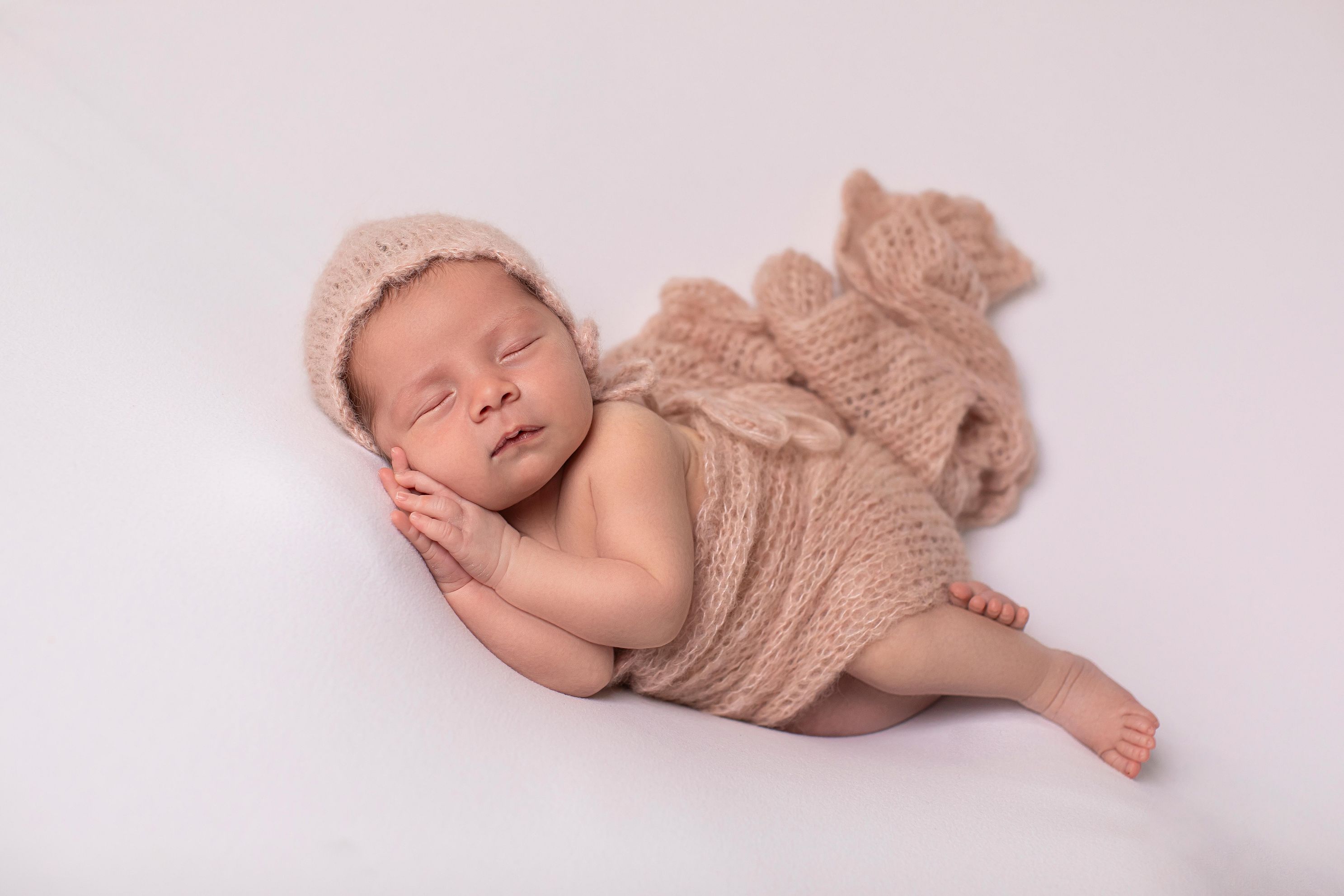 Pink wrap with matching bonnet, side lying position in home studio. Accredited Photographer