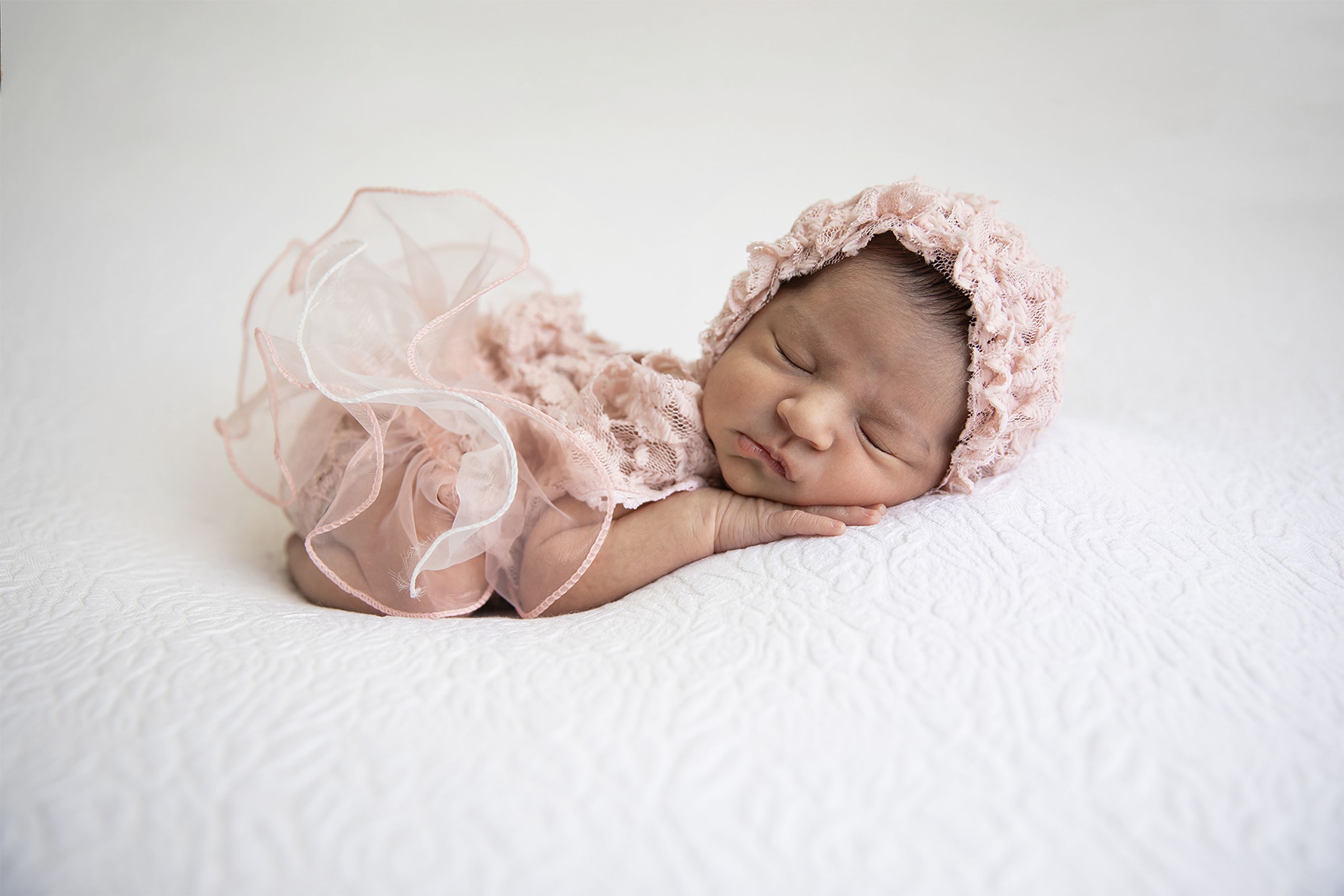 Newborn baby girl in pink dress handmade with matching bonnet, in studio photography accredited