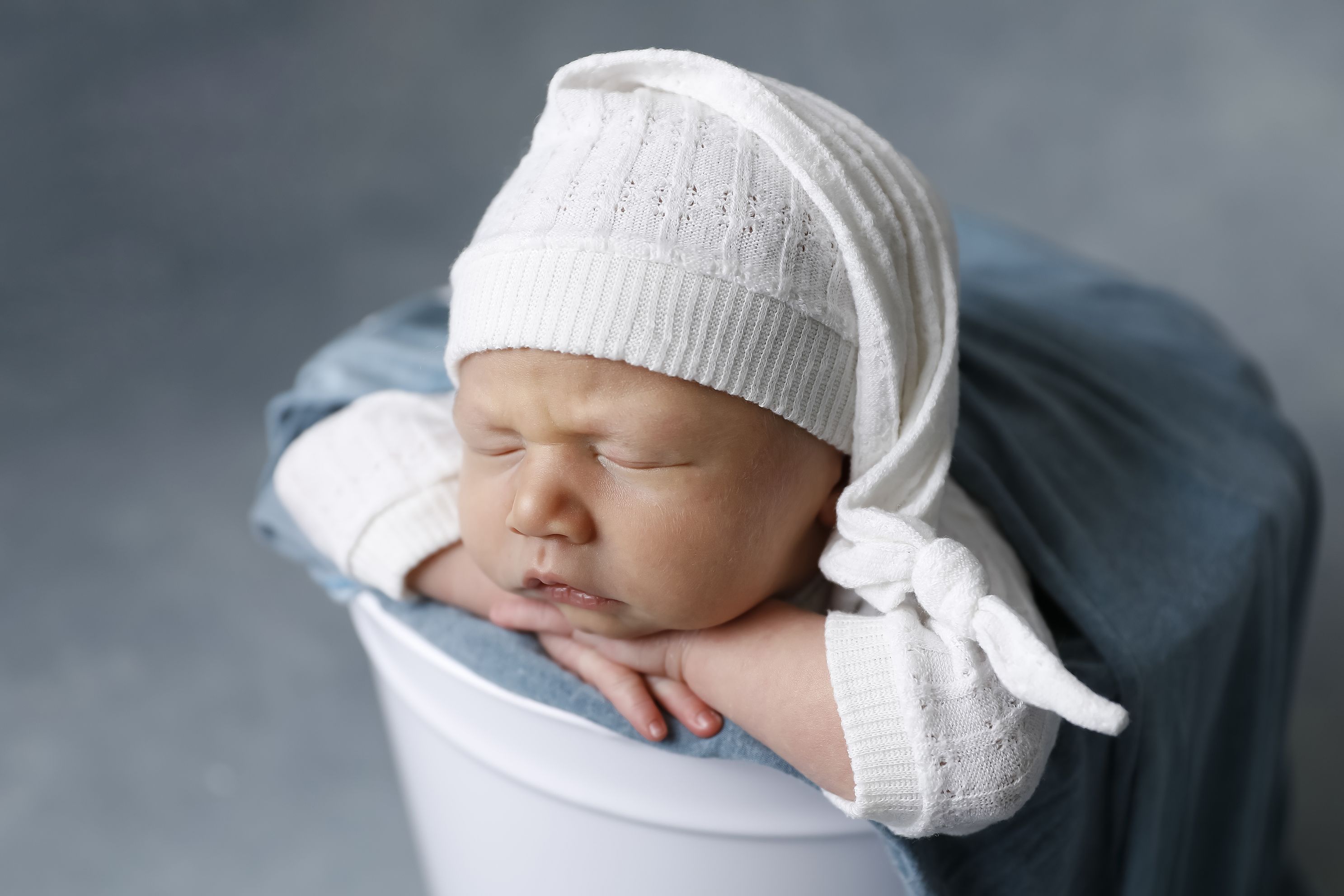 Newborn 9 days old boy in bucket, simple White outfit with matching sleepy hat, Green Aqua layers