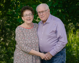 Family photography of laughing grandparents facing each other holding hands