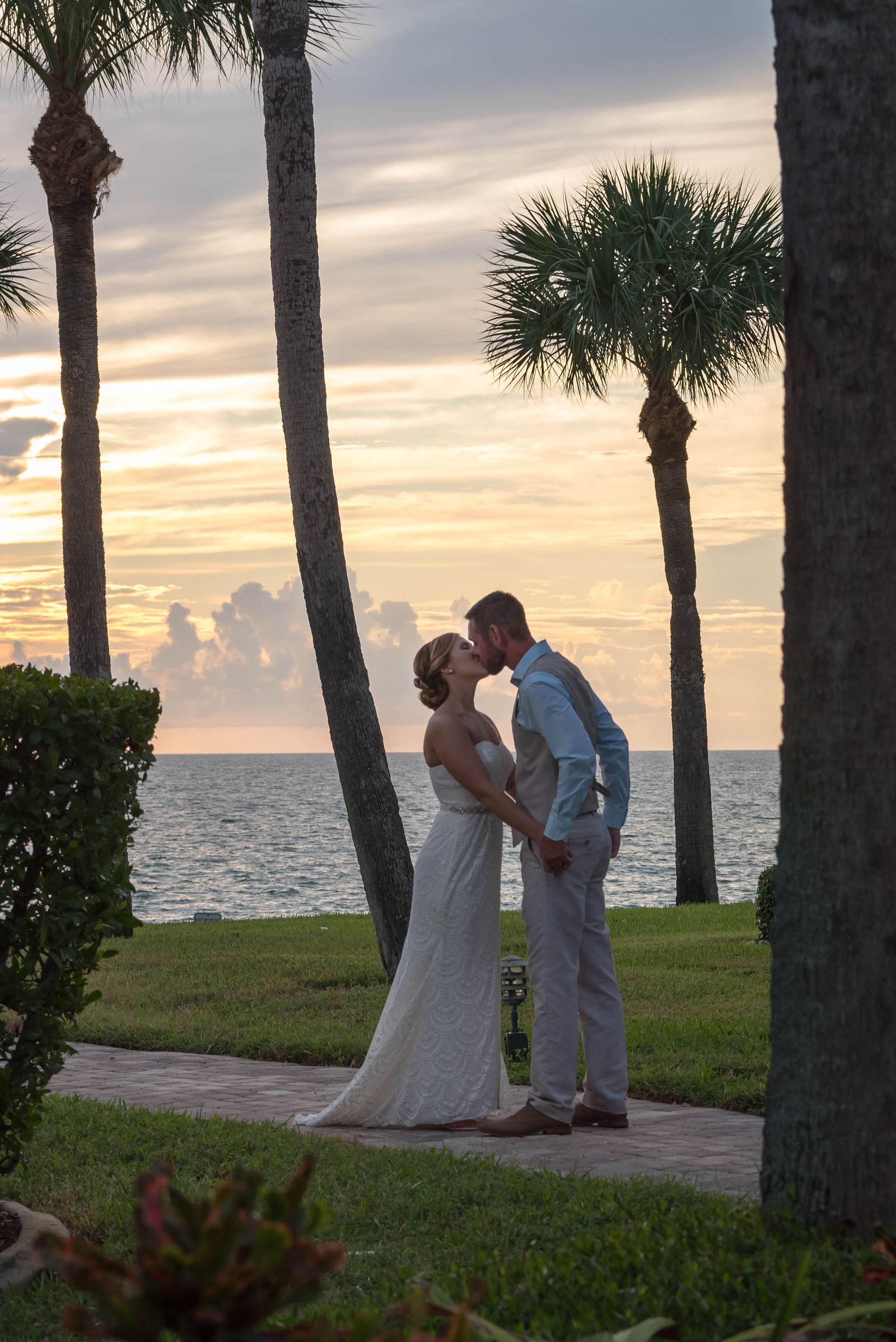 Naples wedding photographers capture bride and groom kissing as the sun sets behind them