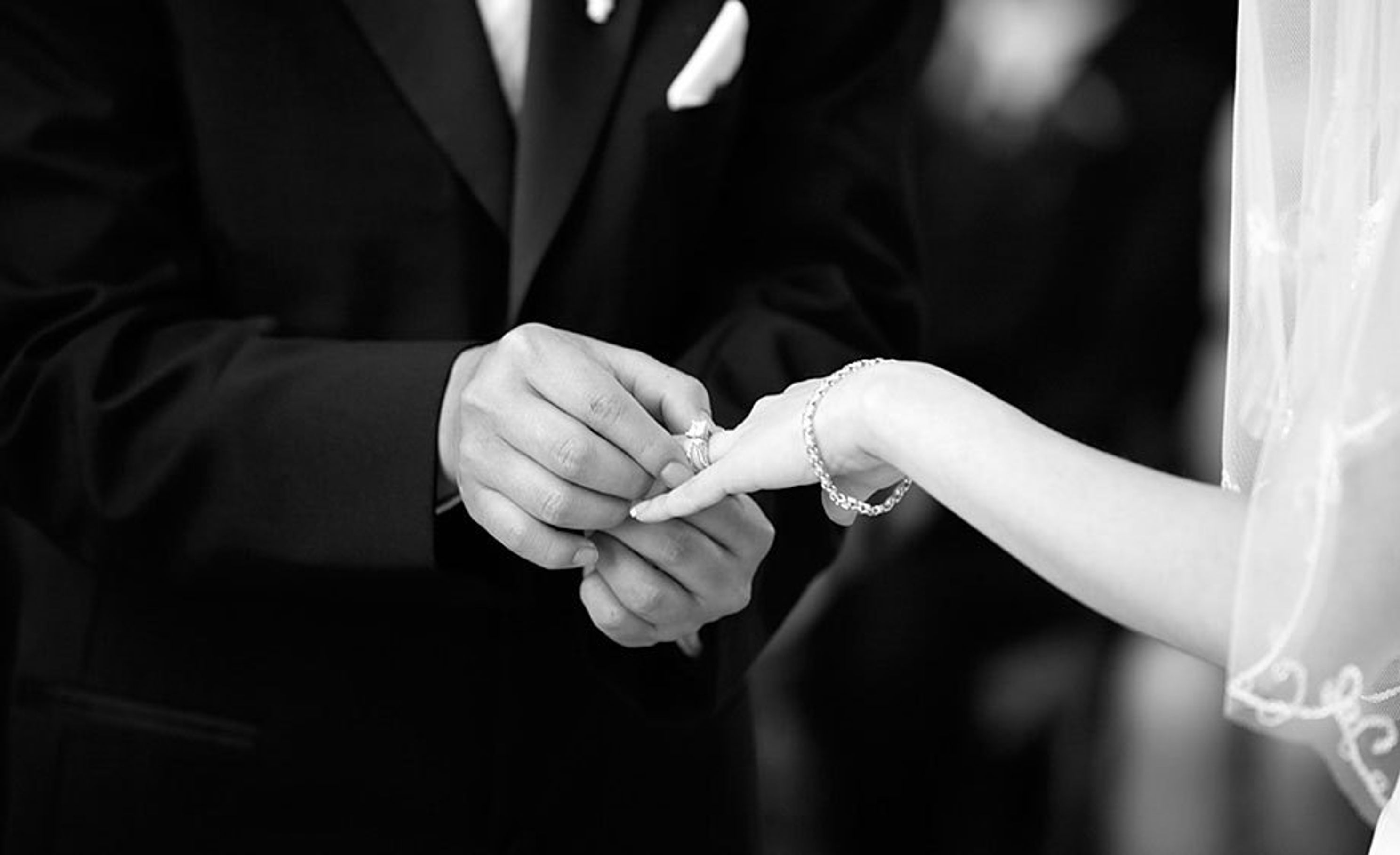   A groom gently places the brides ring on her finger