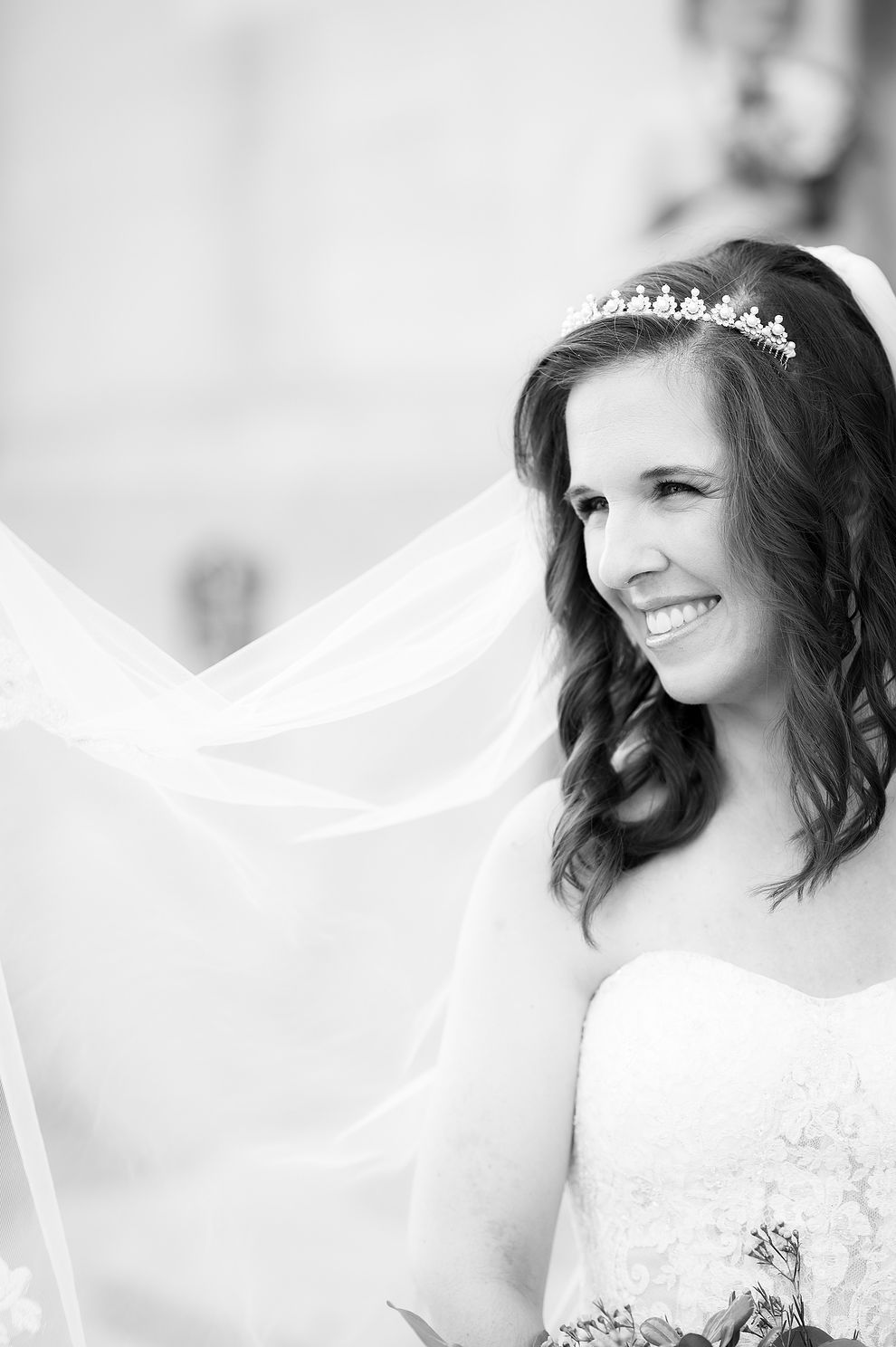 Black and white photo of women looking away and smiling on her wedding day.