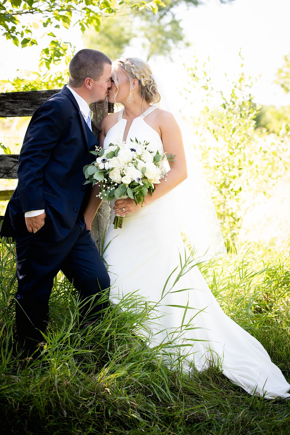 Couple by a fence kissing on their wedding day.