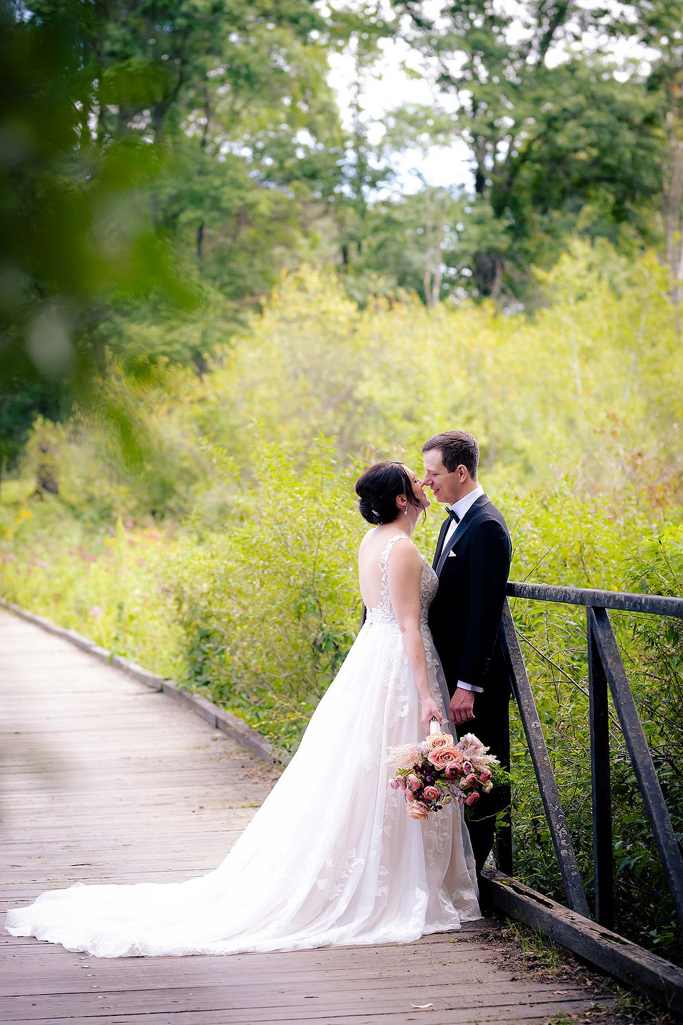 Couple kissing on a bridge as wedding photographer captures the moment.