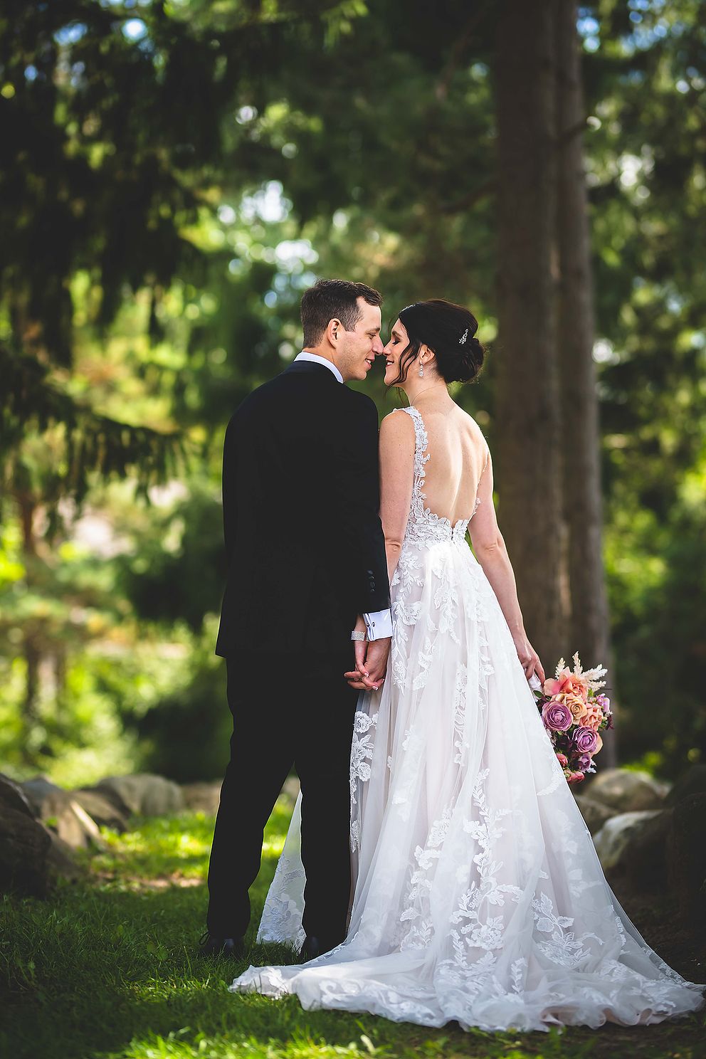 Couple romantically kissing in the woods on their wedding day.