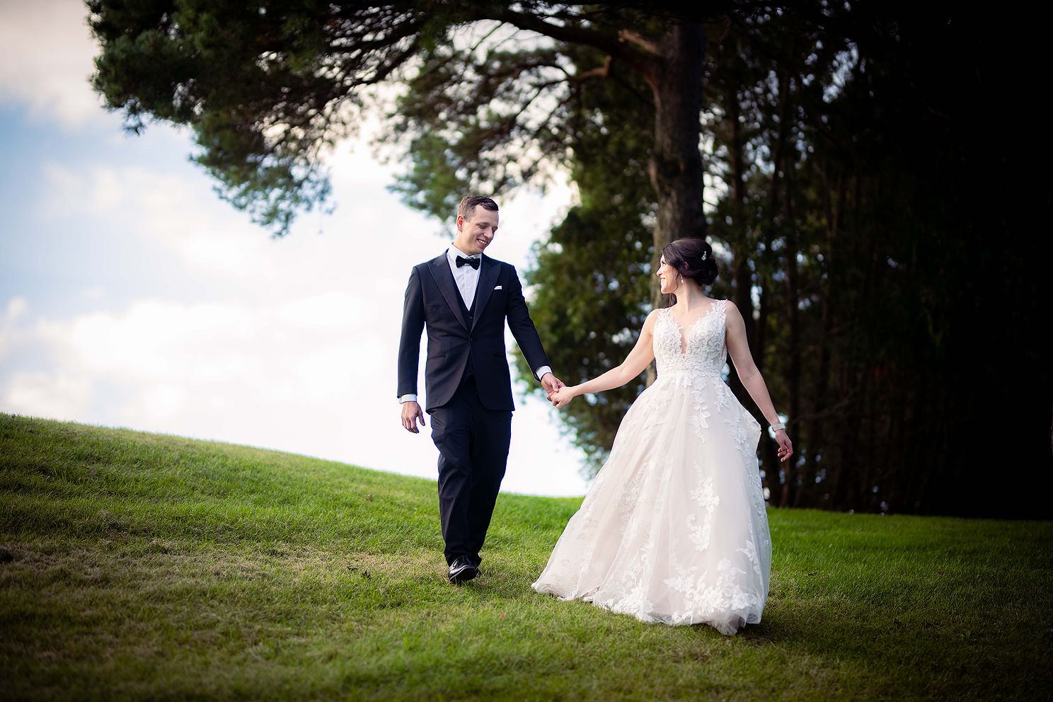 Bride and Groom being Photographed walking down a hill on their wedding day.