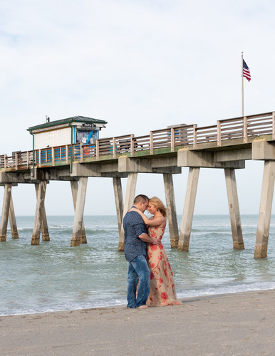 engaged couple kissing in front of Venice Fishing Pier during their morning photo session