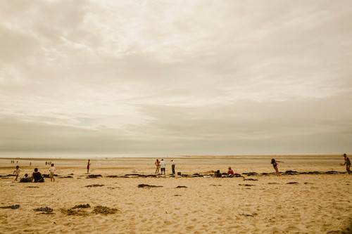 Wide angle shot sandy beach at Hauteville-sur-mer, Normandy, part cloudy sky, people on beach