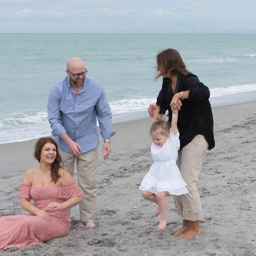 Stephanie Snow swings a couples daughter around on the beach to keep her smiling during family shoot